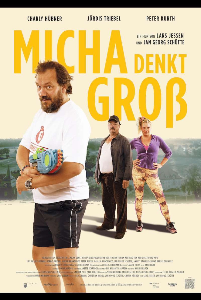 Filmplakat zu dem Film "Micha denkt groß". Vorne ist ein mittelalter weißer Mann mit Wasserpistole zu sehen. Im Hintergrund schauen ein älterer Mann und eine bunt gekleidete Frau trotzig in die Kamera.